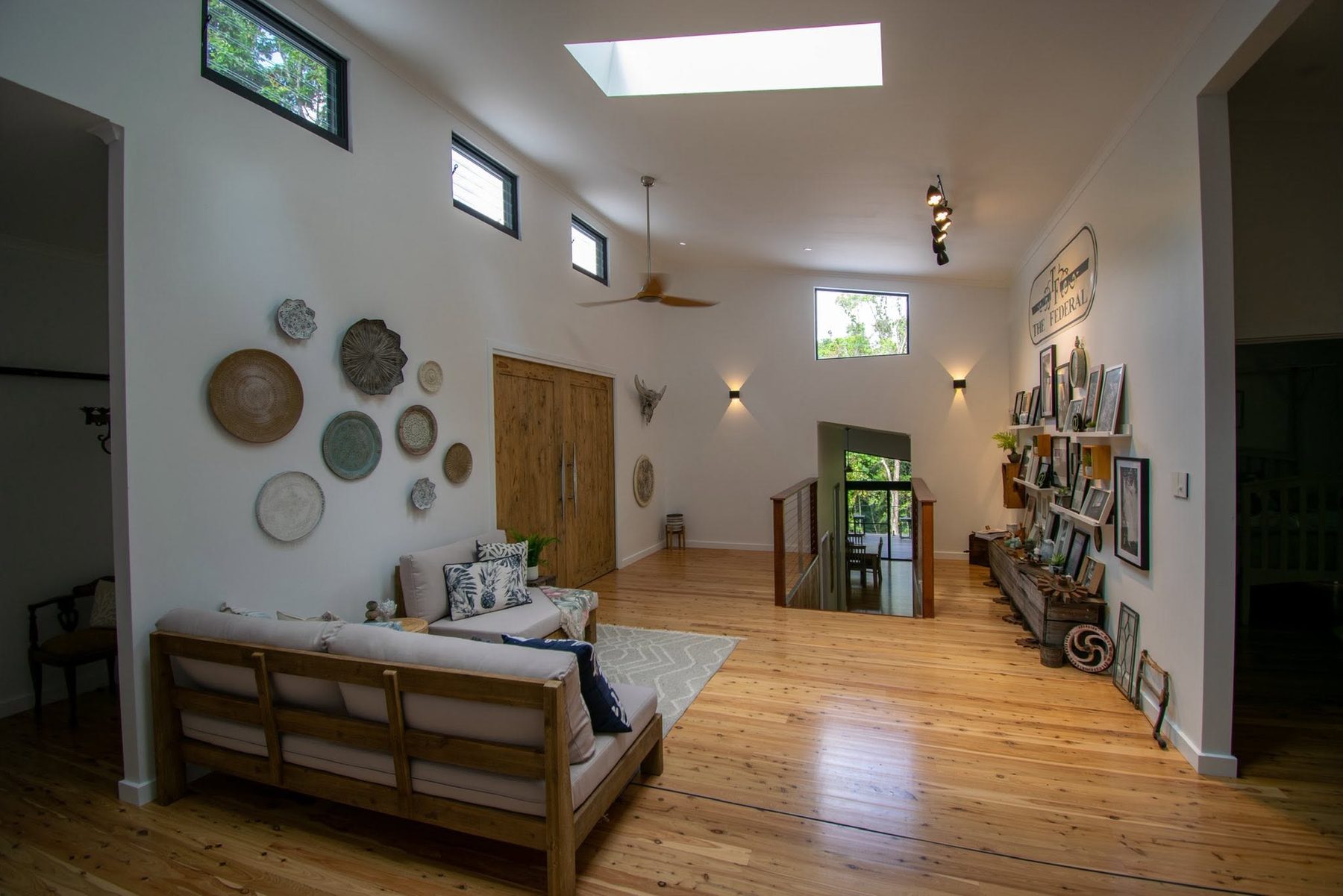 The hallway with a skylight, track lighting and wall lights running its length