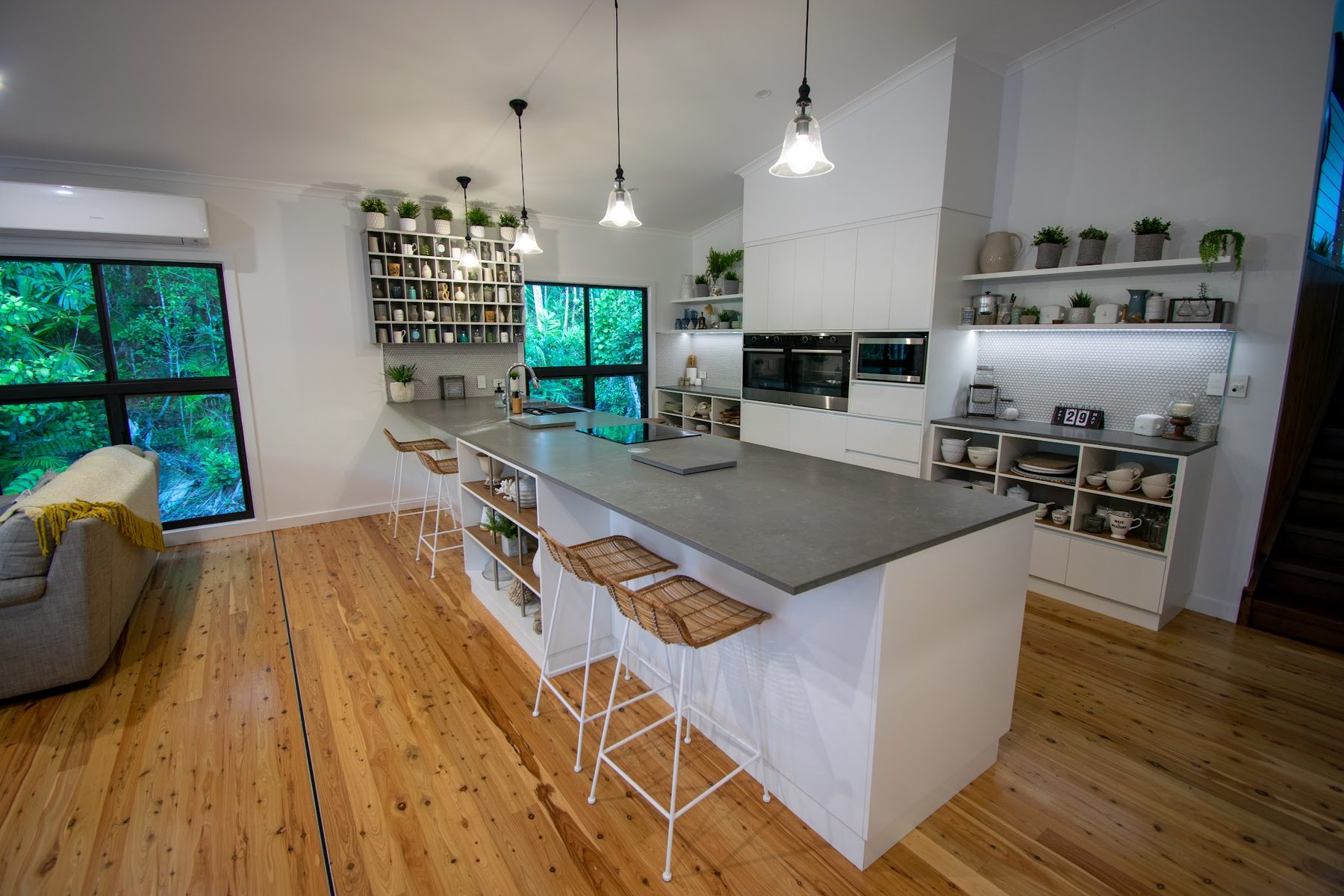 The kitchen with bell pendants over the island and lit shelving behind