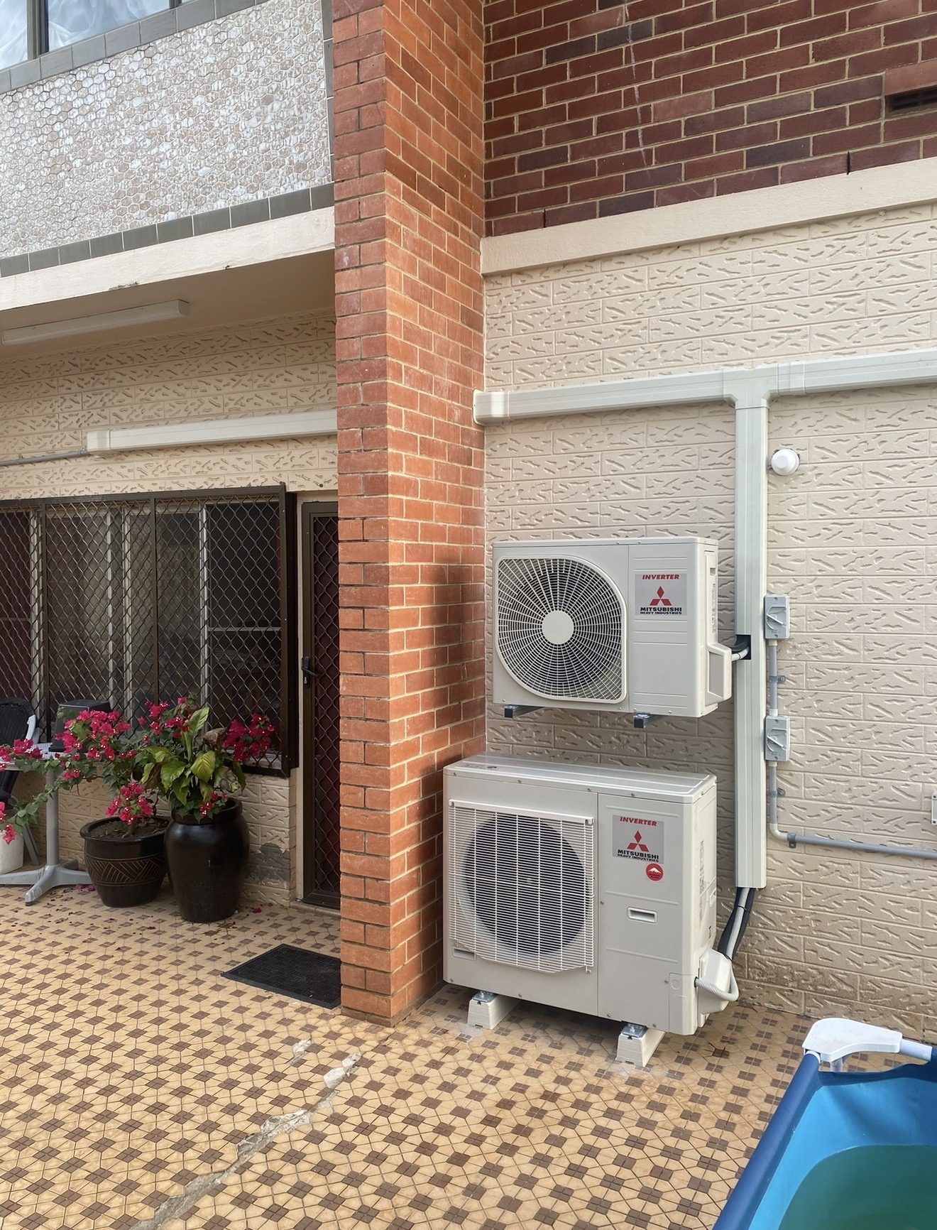 Two Mitsubishi Heavy Industries outdoor air conditioning units mounted on a brick home
