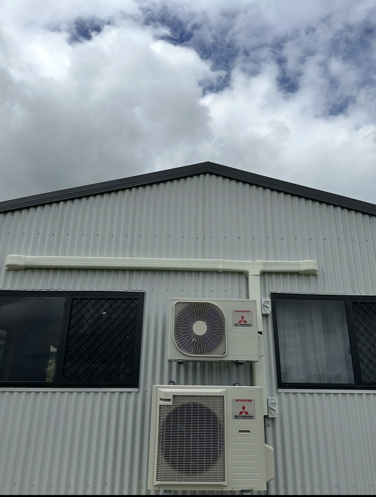 Two outdoor air conditioning units and their ducting on the gable of a colorbond shed